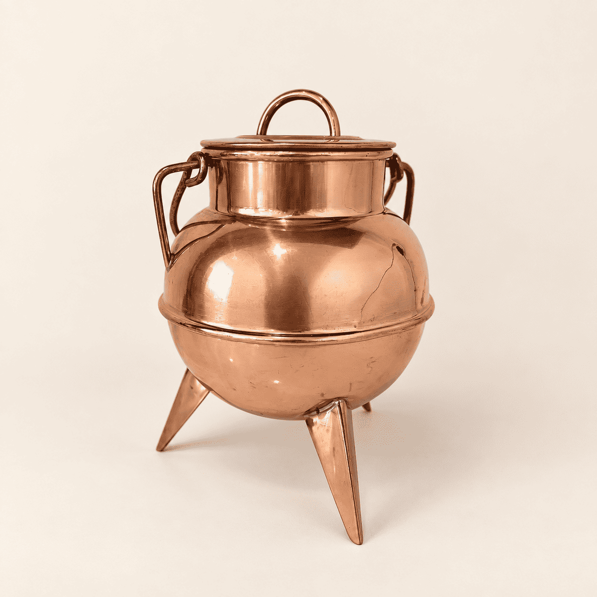 Copper footed cauldron with lid and swing handle, front view on three spike feet