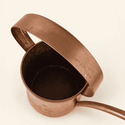 Copper watering can at an angle with the rose spout and handle