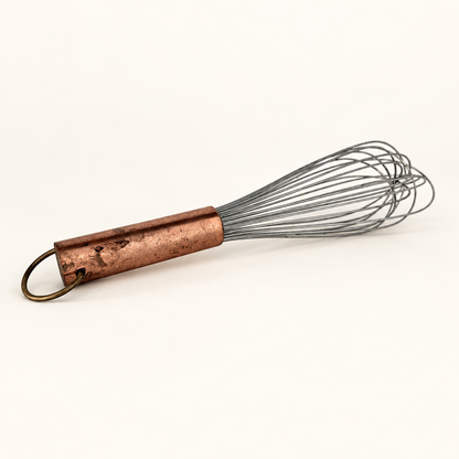 Vintage balloon whisk with a copper handle and brass hanging ring, full view