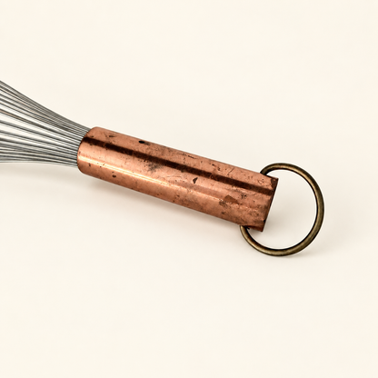Copper handle and brass ring of the whisk with the wires to the left