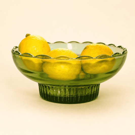 E.O. Brody green glass pedestal bowl with open lace rim, holding lemons
