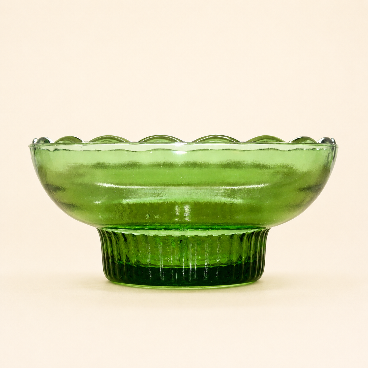 Side profile of E.O. Brody green glass pedestal bowl with reeded foot