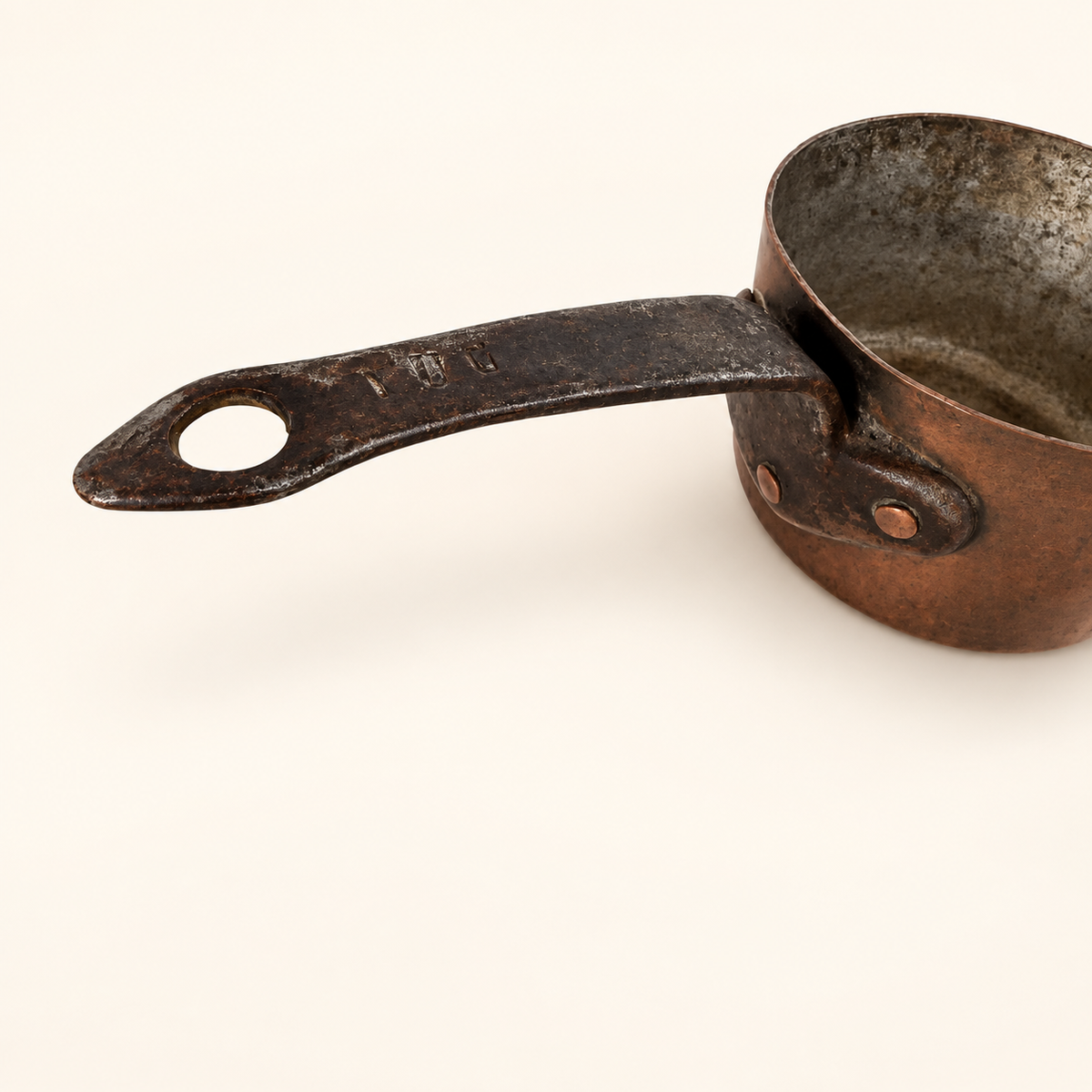 Forged iron handle with a hanging eye and stamped marks, copper rivets at the flange