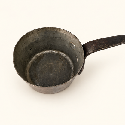 Worn tin lining inside the copper saucepan, handle to the right