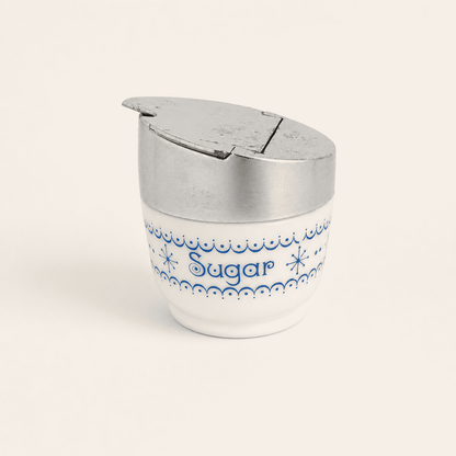 Gemco milk glass sugar dispenser with blue snowflake garland and flip lid, front view