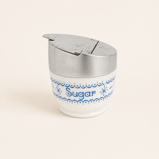 Gemco milk glass sugar dispenser with blue snowflake garland and flip lid, front view