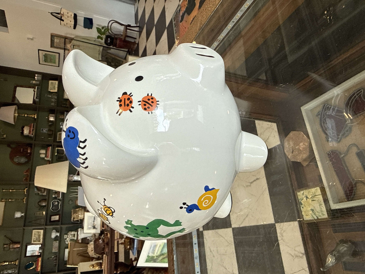 Hand-painted ceramic piggy bank with animals and insects in primary colors