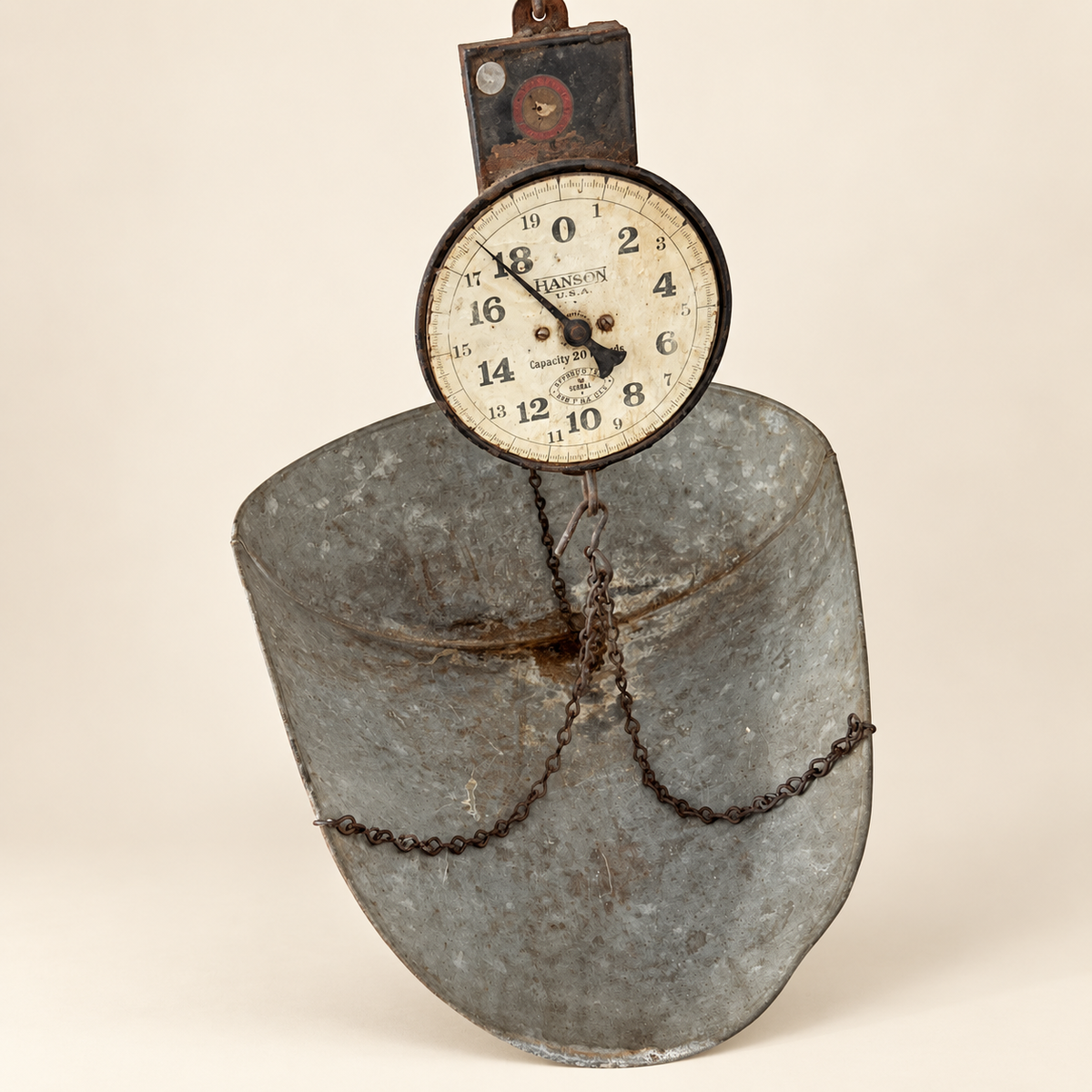 The scale hanging with the dial at top and the galvanized scoop below on its chains