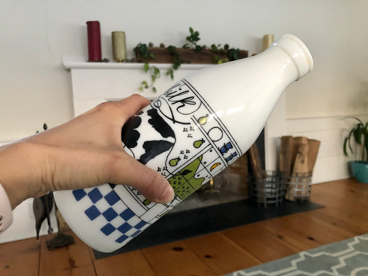 Hand holding the Alan Wood milk glass bottle on its side