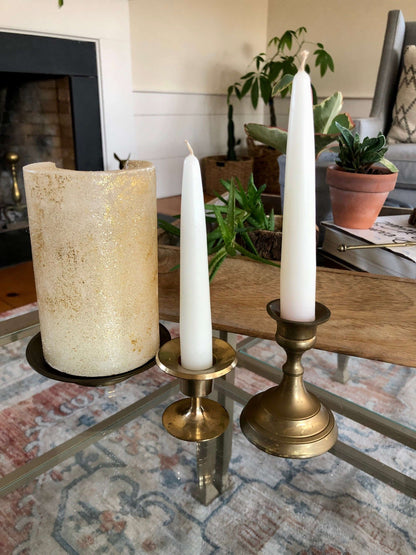 Vintage brass candlesticks with white tapers on a glass table