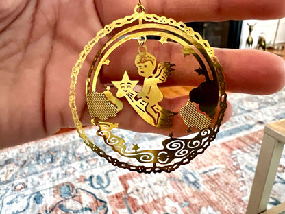 Etched brass Christmas ornament of an angel riding a shooting star, round relief design — detail view