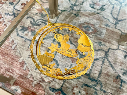 Etched brass Christmas ornament of an angel riding a shooting star, round relief design — detail view