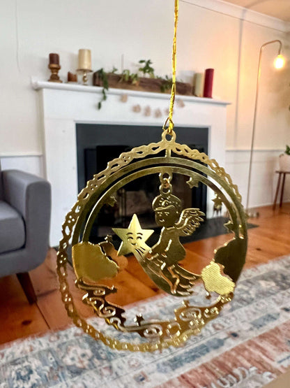 Etched brass Christmas ornament of an angel riding a shooting star, round relief design — detail view