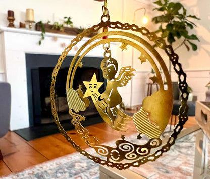 Etched brass Christmas ornament of an angel riding a shooting star, round relief design — detail view