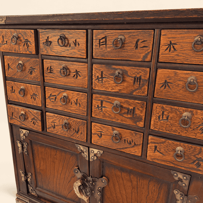 Close view of figured elm drawer fronts with carved characters and brass ring pulls