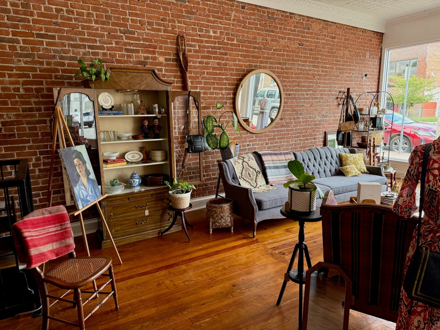 Curated vintage furniture, home decor, and brass inside Loom Vintage's shop — exposed brick, tufted sofa, and antique mirrors