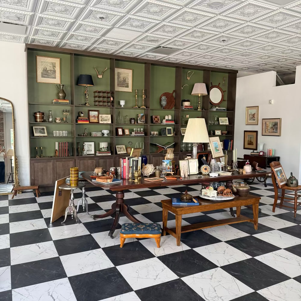 Inside the Loom Vintage shop in Fairfield, CT: green shelves of vintage glass, brass and framed art above a checkerboard floor.