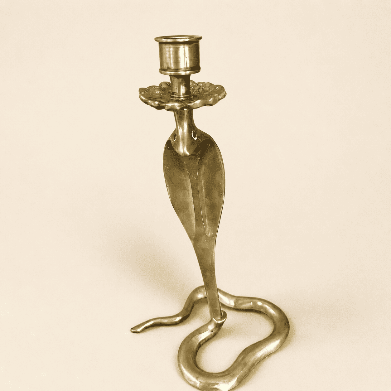 Angled view of brass cobra candlestick showing flared hood and candle cup