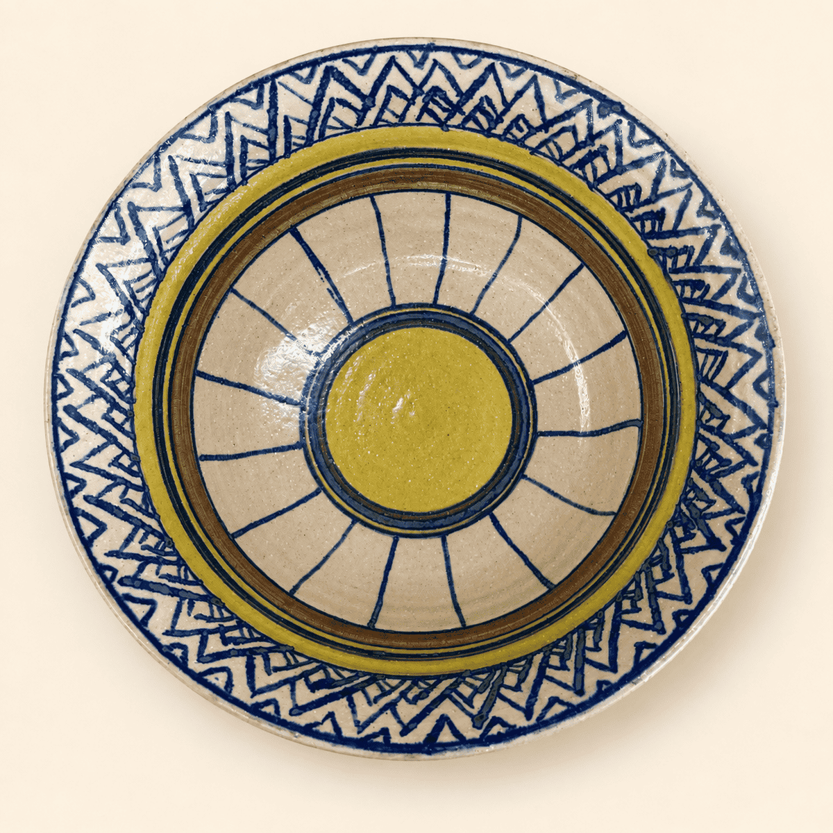 Top-down view of signed studio pottery bowl with geometric blue and olive pattern