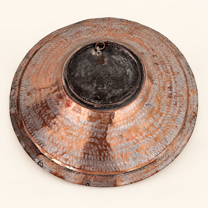Back of the copper charger at an angle showing the raised domed center and copper hanging ring