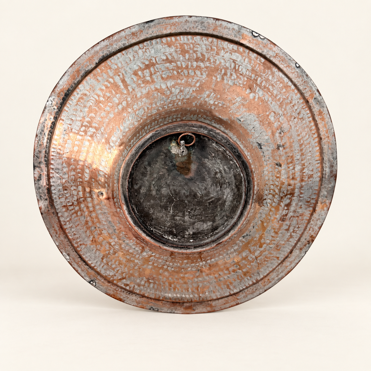 Back of the charger with the copper hanging ring at the center and dense hammered texture