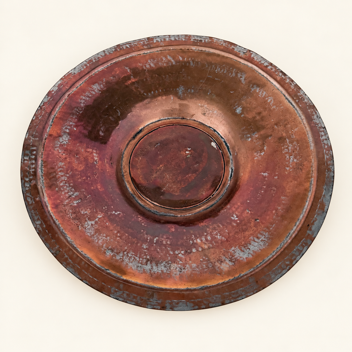 Face of the tinned copper charger, hammered well with a raised center medallion and scalloped rim