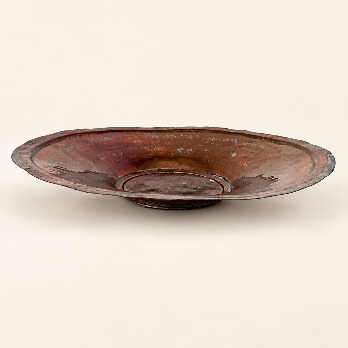 Tinned copper charger seen in profile, shallow dished form with a raised center and scalloped rim