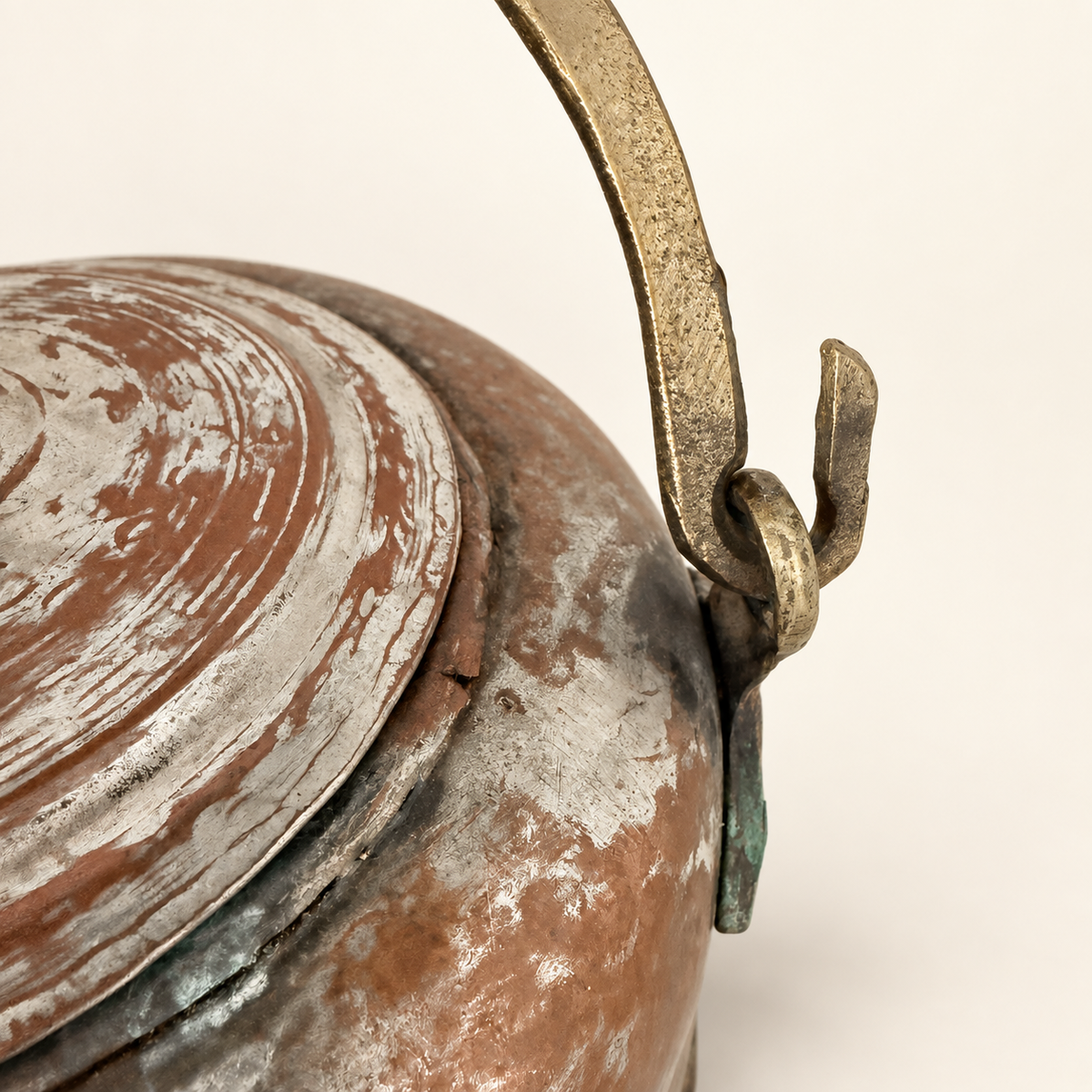 Brass bail hooked into the lug on the kettle shoulder, close detail with green verdigris