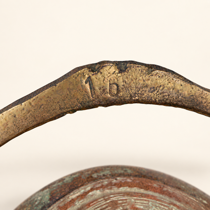 Close detail of a stamped mark on the arched brass bail handle