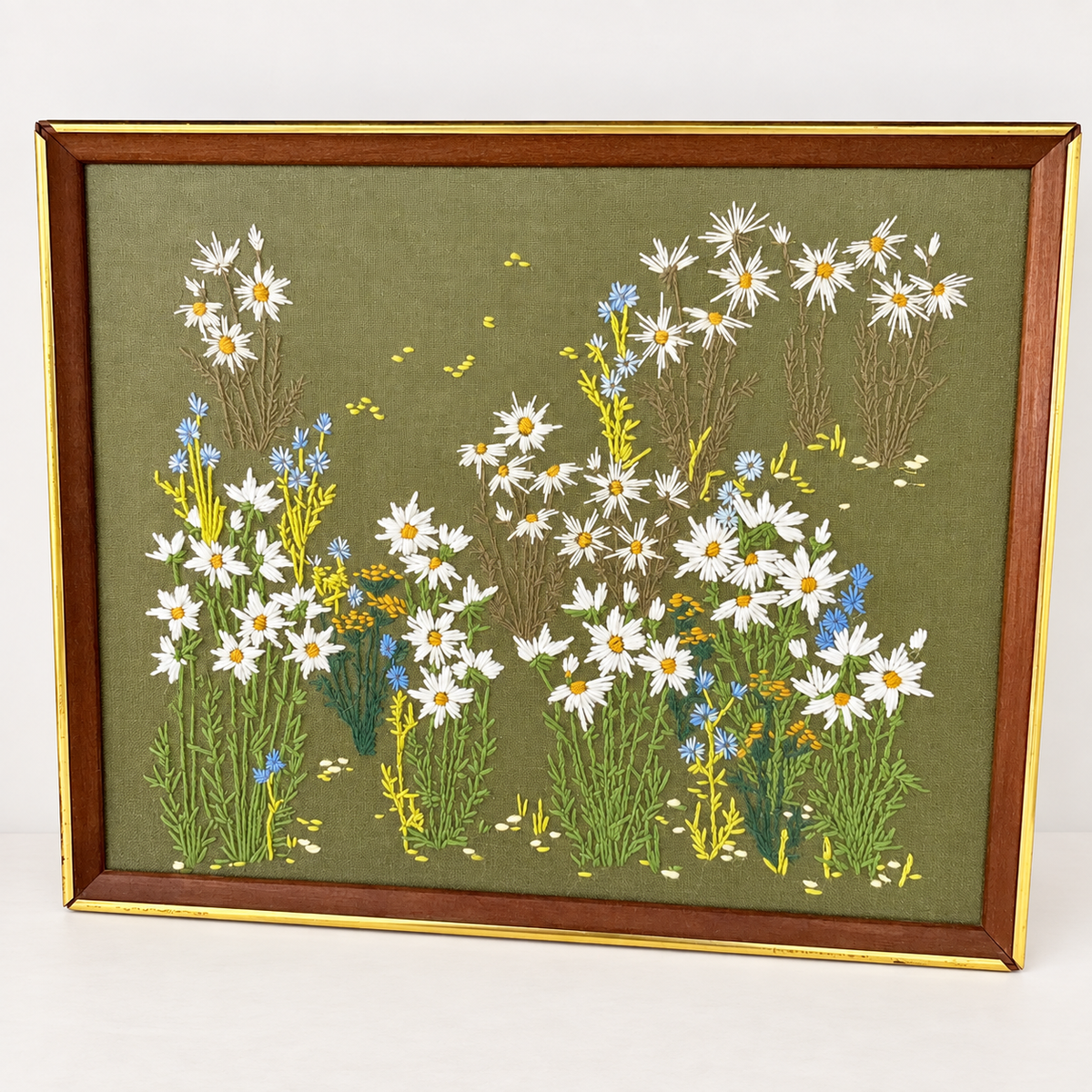 Vintage 1970s crewel embroidery of wildflower meadow with daisies and cornflowers on olive green, framed, photo 1 of 5