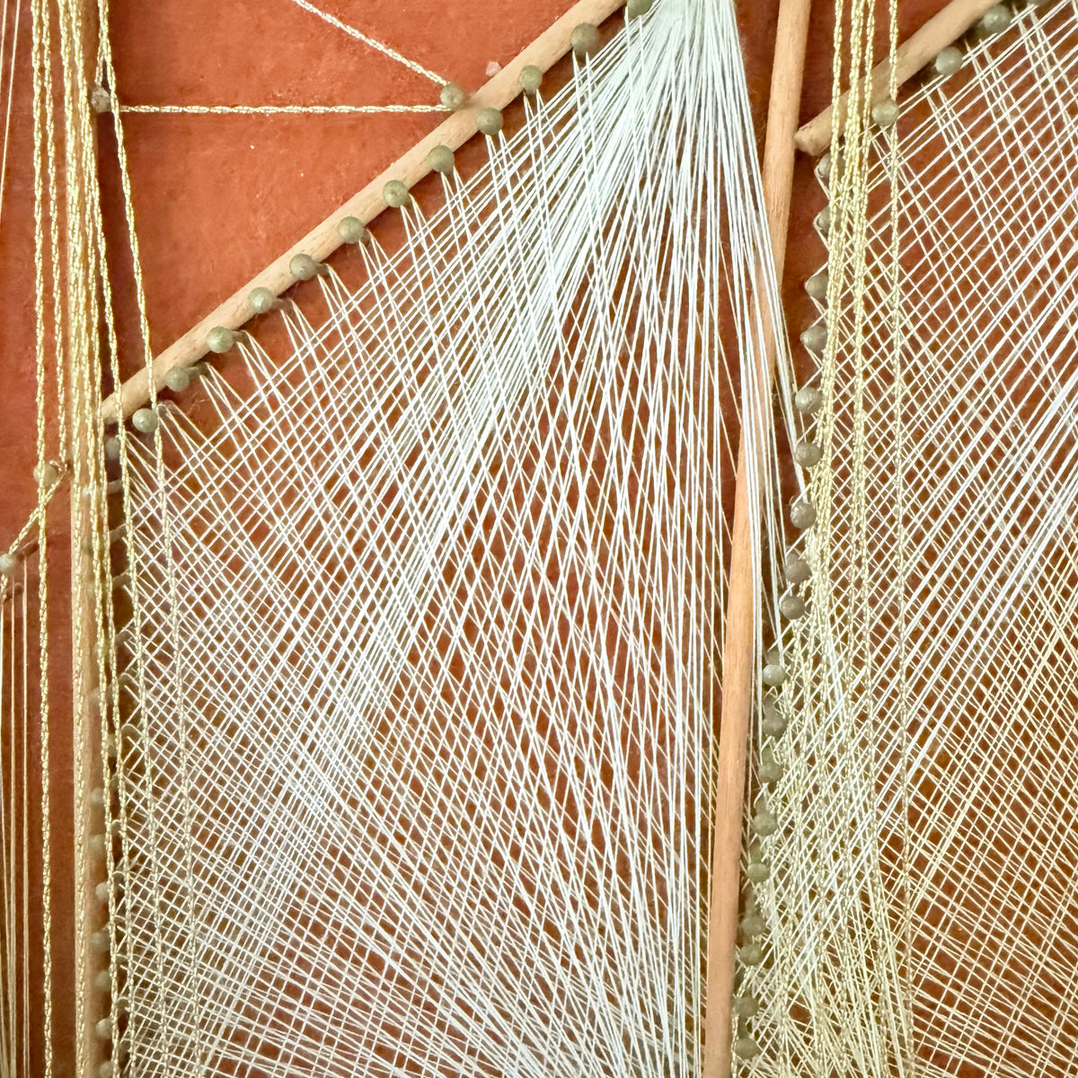 Detail of crisscrossed white and gold thread on string art sail, photo 4 of 5