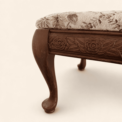 Detail of a cabriole leg and pad foot on the carved footstool