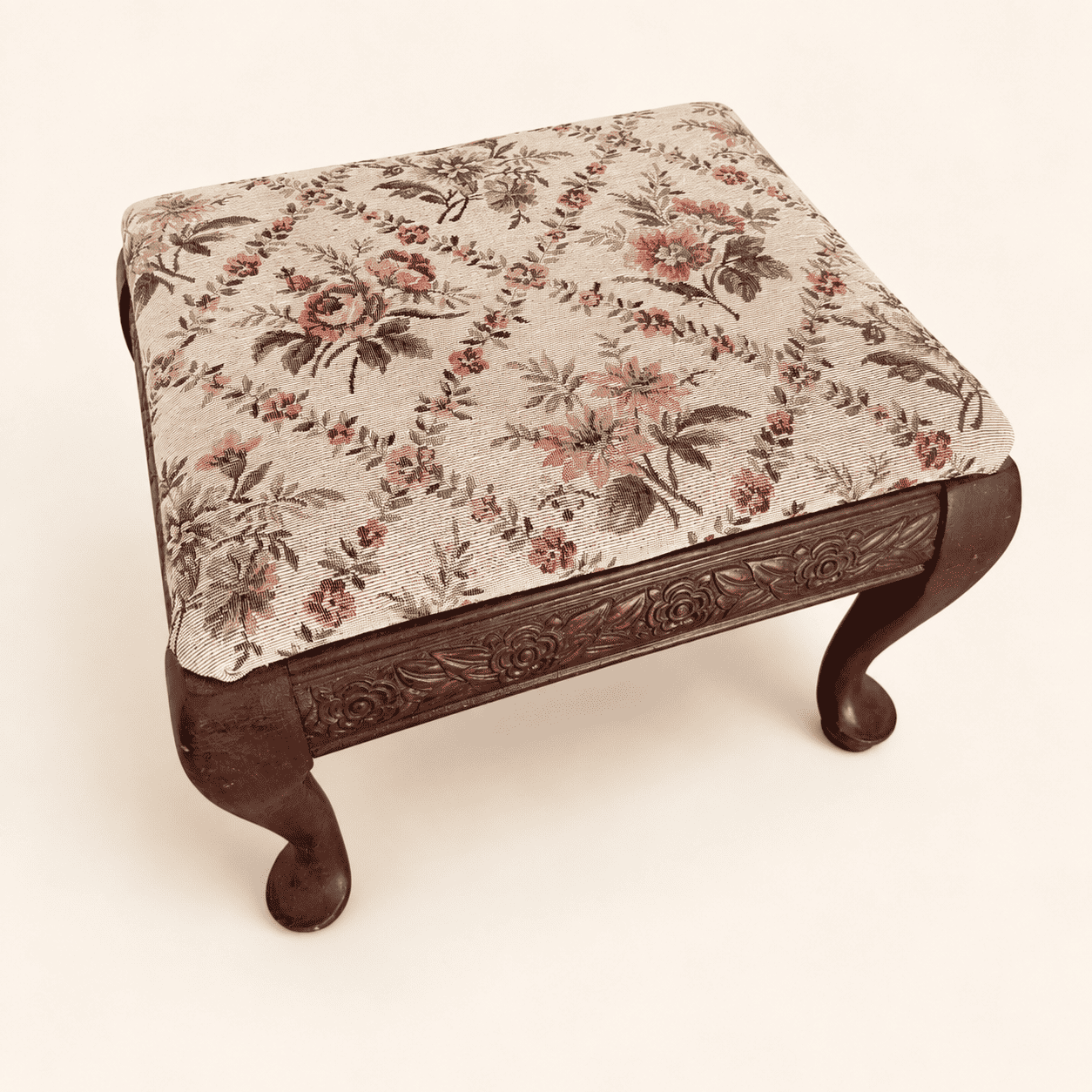 Top-down view of the floral tapestry seat on the carved footstool