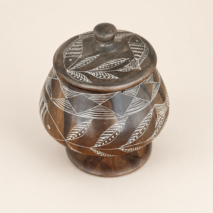 Top view of soapstone jar lid with etched fish and leaves