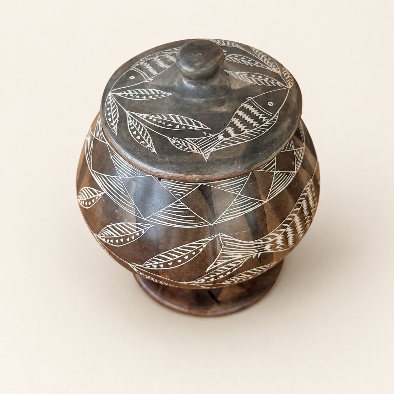 Top view of soapstone jar lid with etched fish and leaves