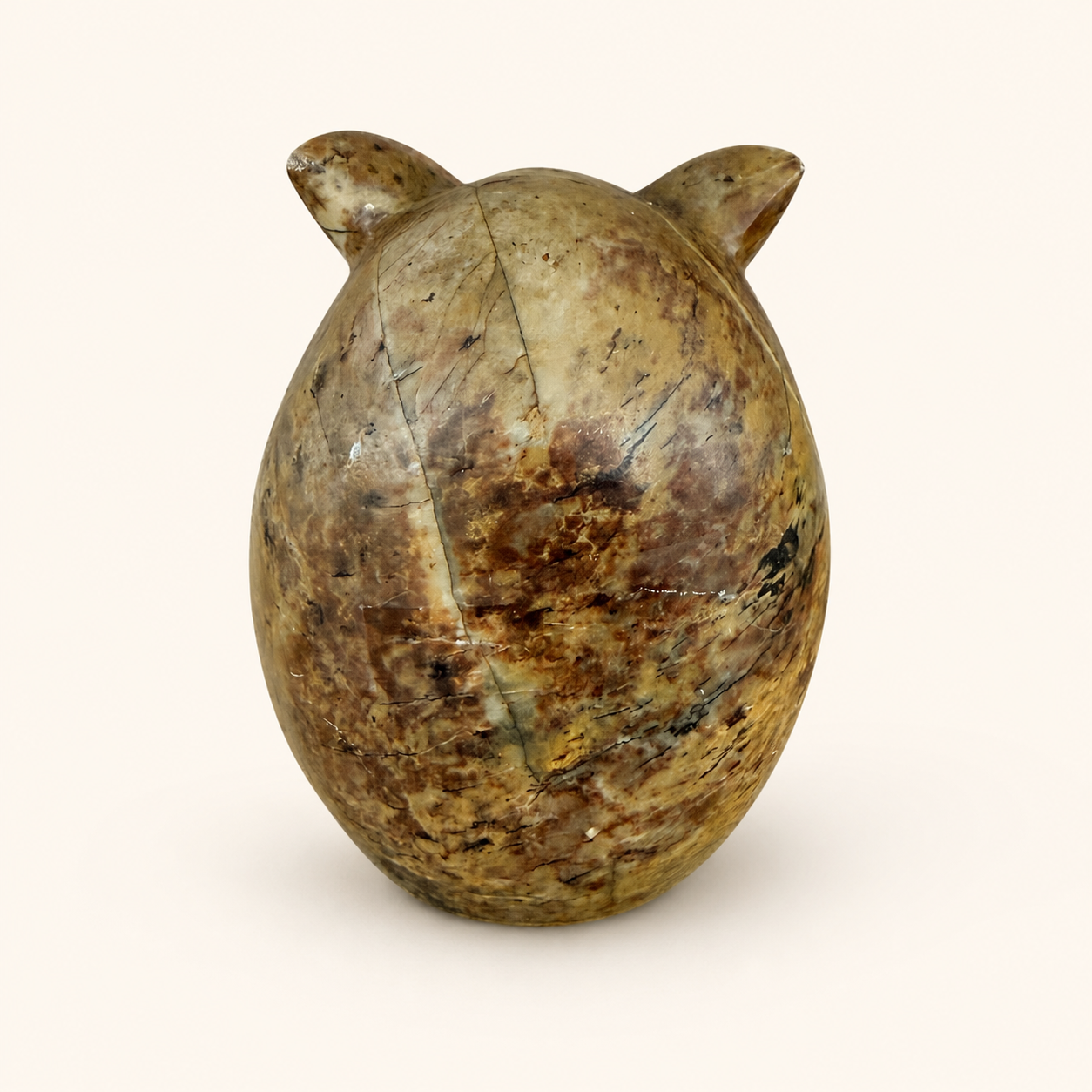 Back view of carved stone owl showing mottled stone and fissures