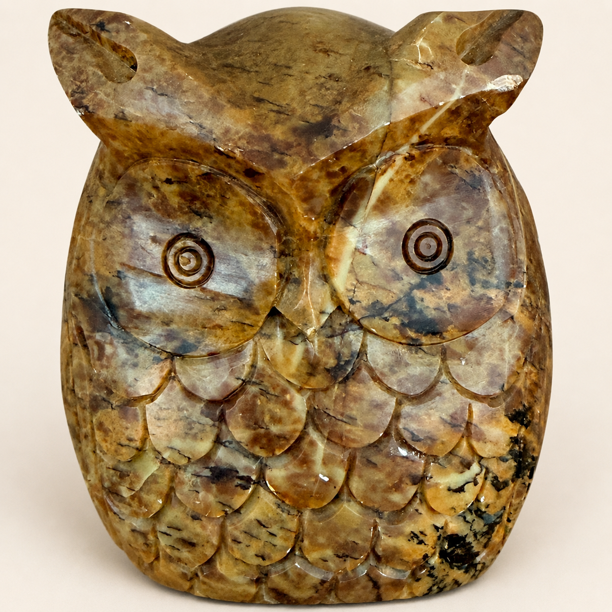 Close-up of carved stone owl face showing concentric eyes and feathers