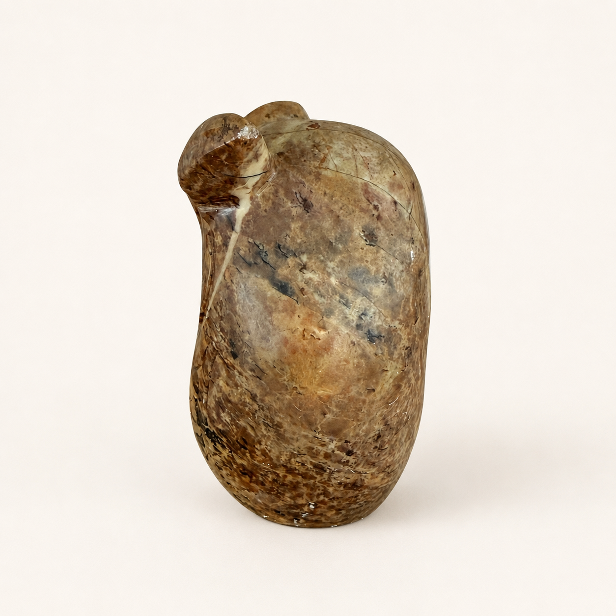 Side view of hand-carved stone owl figurine with natural veining
