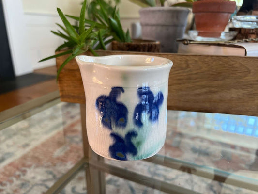 Small hand-painted white cup with a blue floral spray, doubles as a bud vase