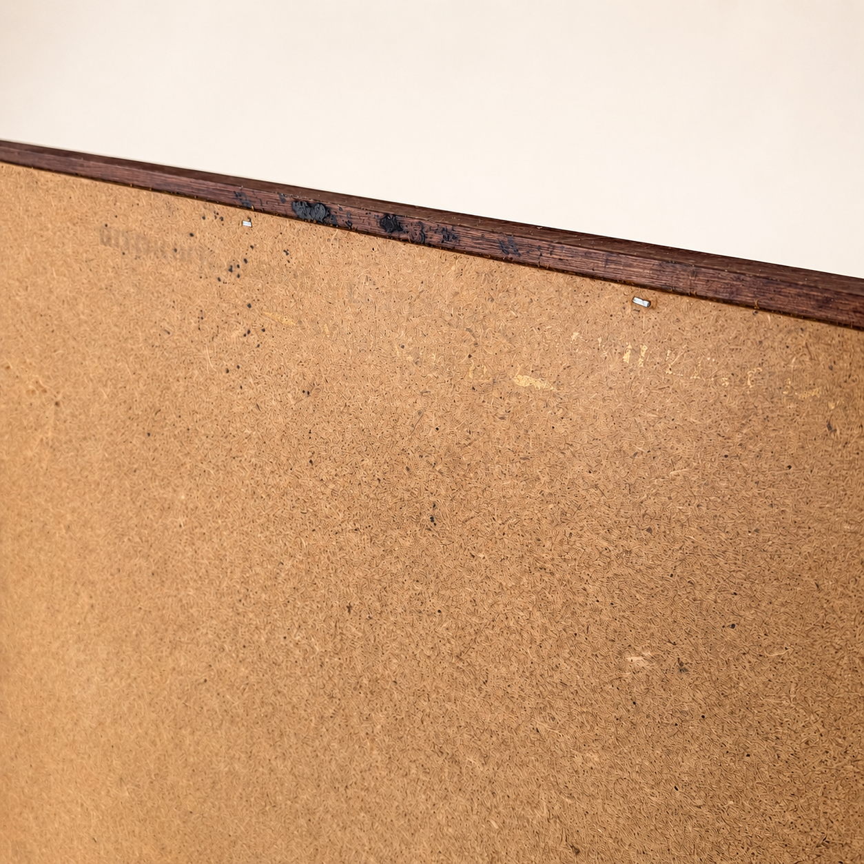 Edge detail of mirror back showing aged hardboard and staples