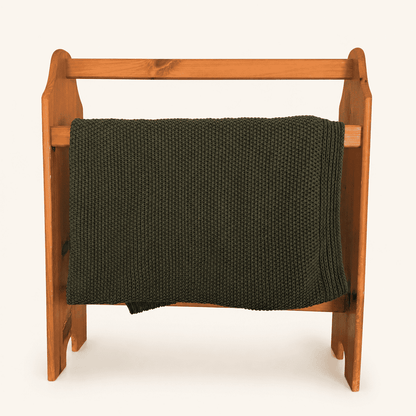 Green knit throw draped over the pine quilt rack rail