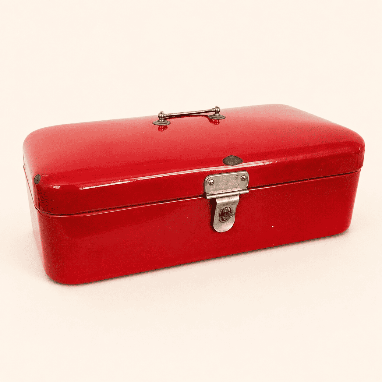 Angled view of glossy red enamelware bread box, closed