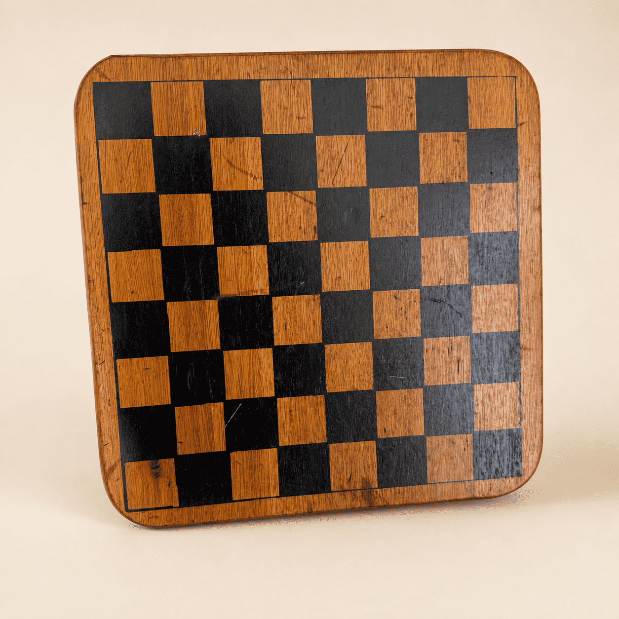 Vintage wooden checkerboard game board with black and natural squares, front view