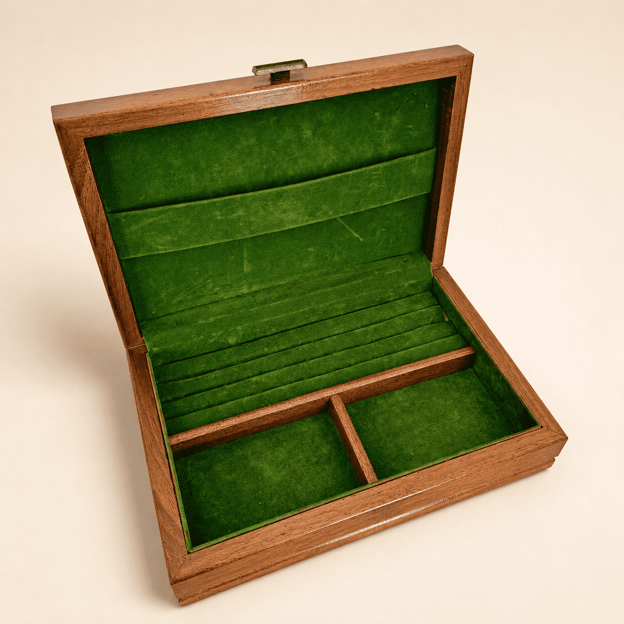 Angled view of open wood jewelry box with green velvet interior