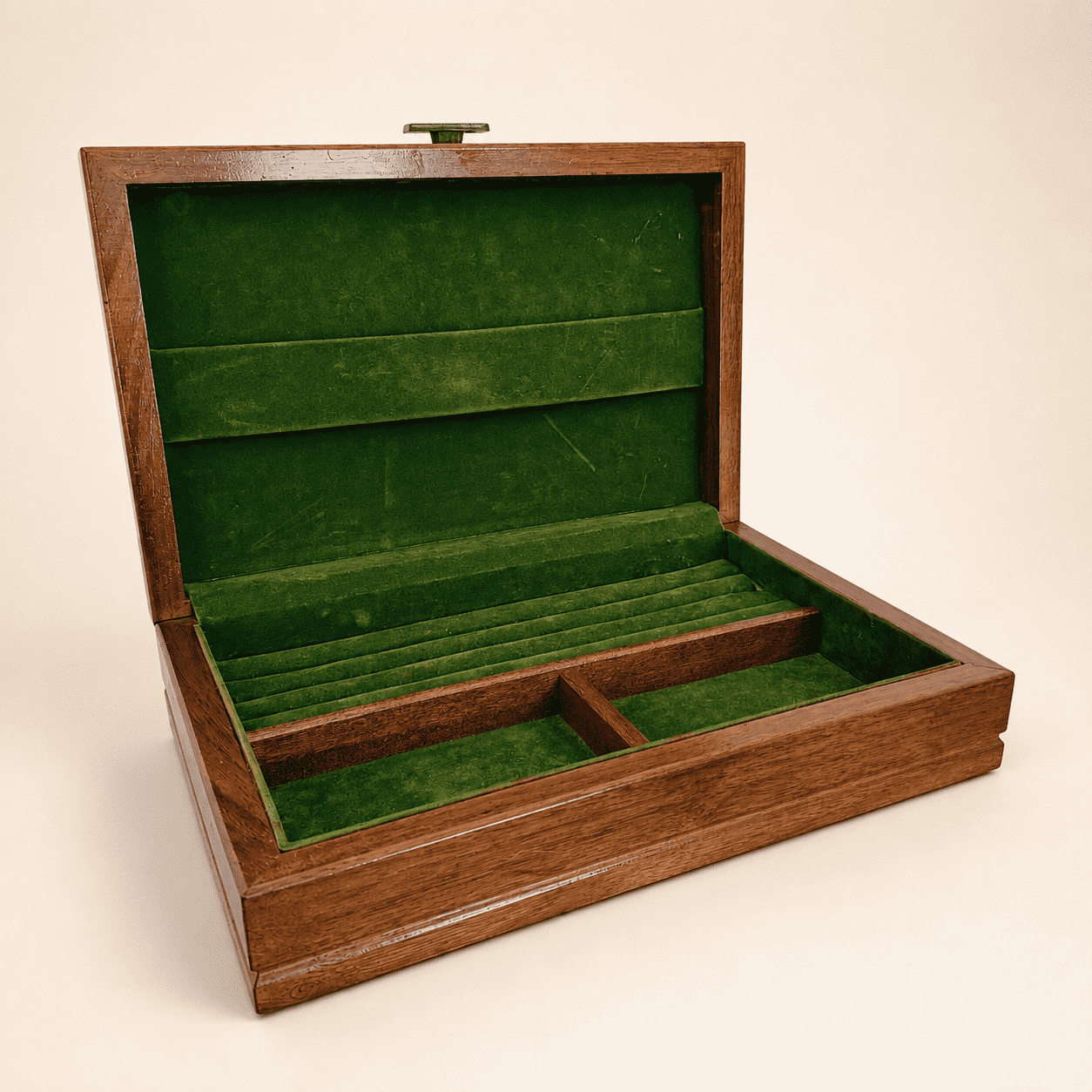 Open vintage wood jewelry box showing green velvet lining, ring rolls, and compartments