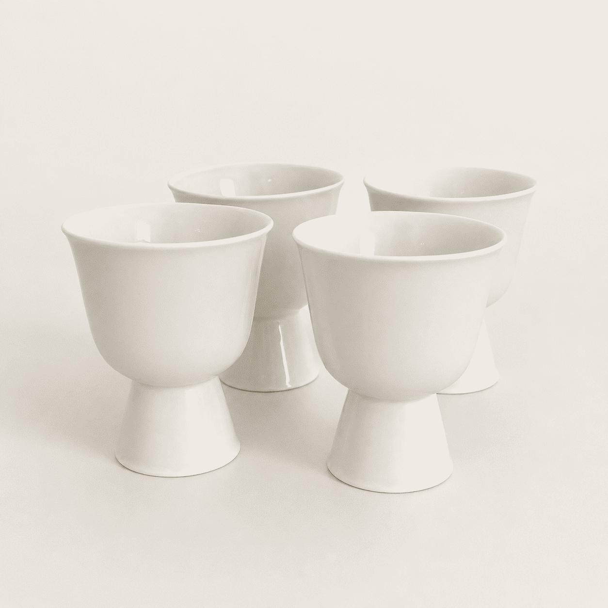Set of four white porcelain footed cups with pedestal bases, front view
