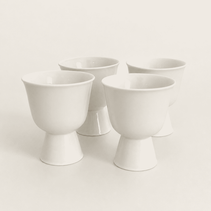 Set of four white porcelain footed cups with pedestal bases, front view