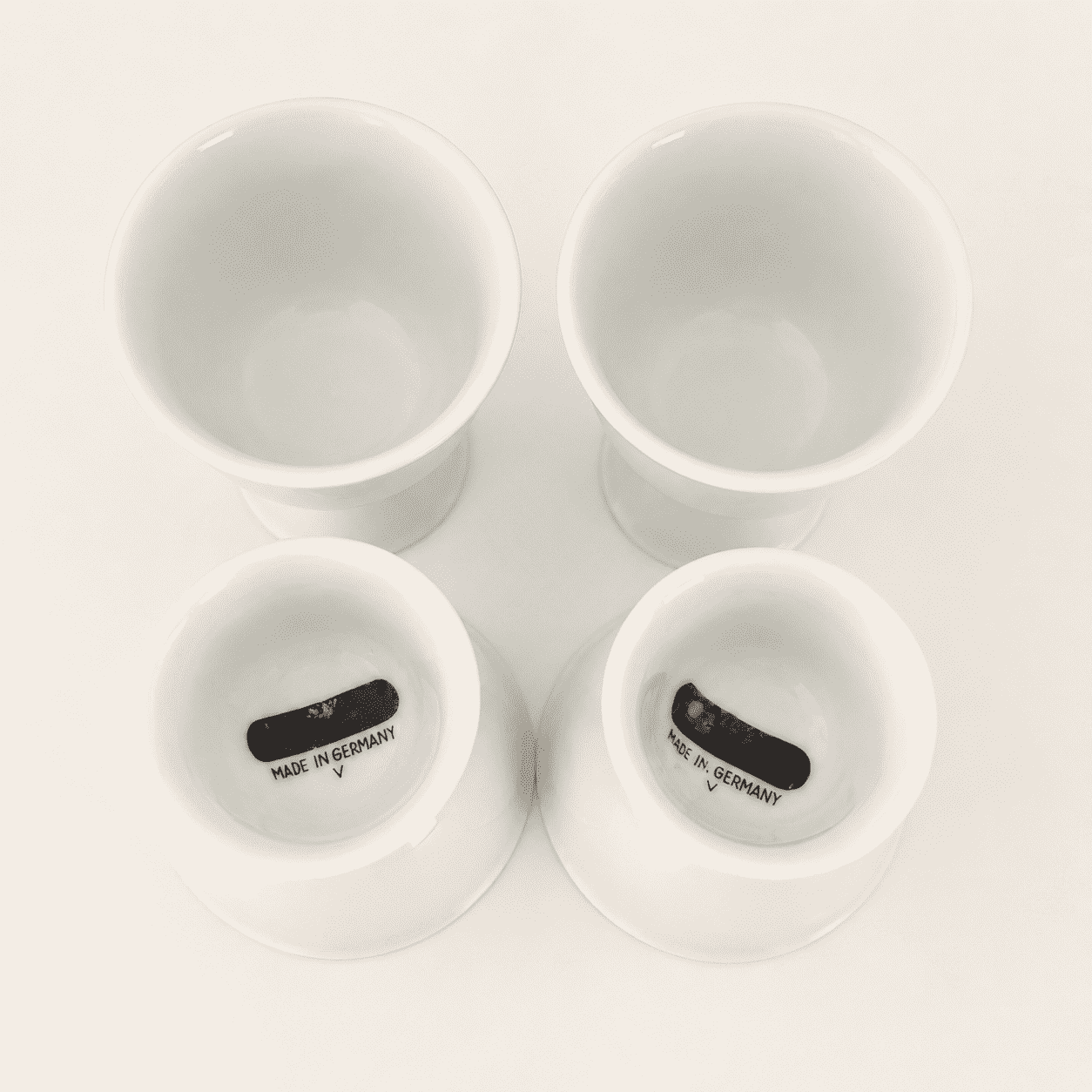 Four white porcelain cups with two turned to show "Made in Germany" base marks