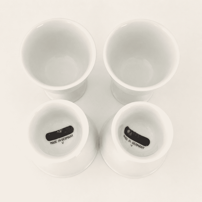 Four white porcelain cups with two turned to show "Made in Germany" base marks