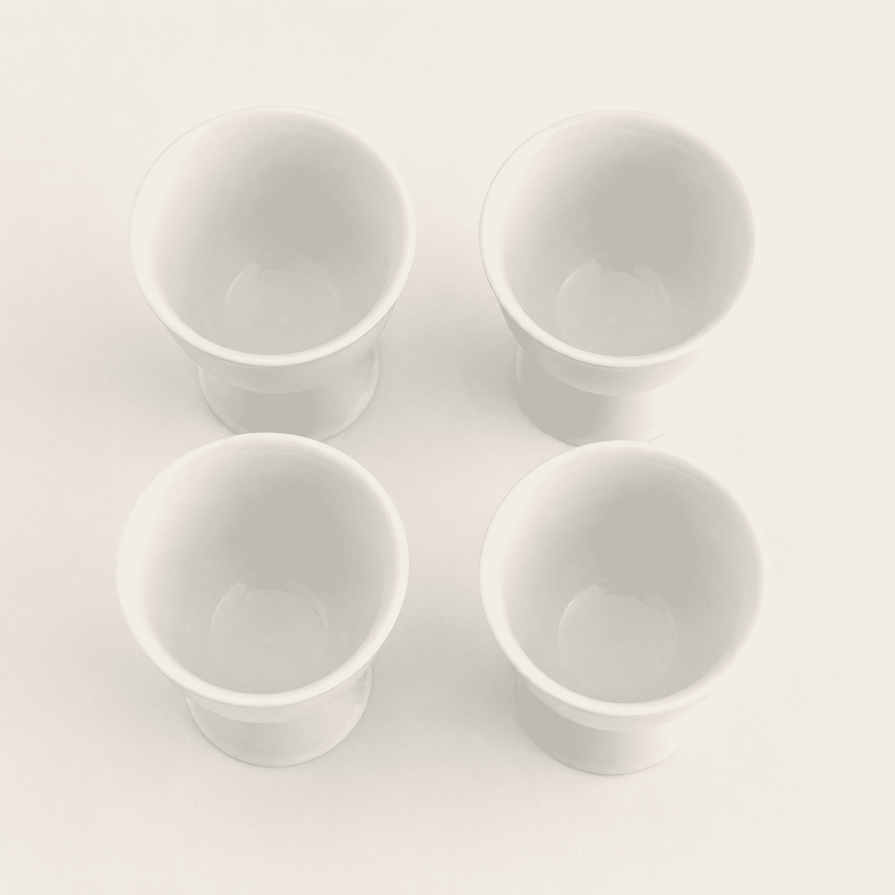 Top-down view of four white porcelain footed cups showing openings